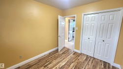 Room featuring wood-finish flooring, warm-toned walls, white baseboards, and a built-in closet with bi-fold doors - 