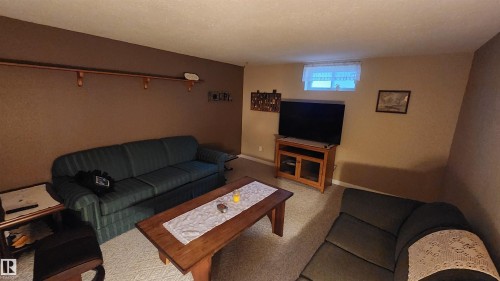 Carpeted living space with a wood-finish coffee table and an integrated wall shelf - 13307 Delwood Road, Edmonton, AB 