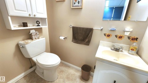 Bathroom featuring a vanity with an integrated sink, a wall-mounted mirror, and a toilet - 13307 Delwood Road, Edmonton, AB 