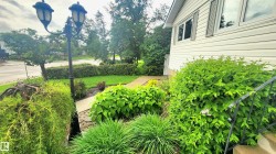 Manicured landscaping with diverse plantings, a concrete walkway, and a decorative street lamp - 