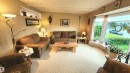 Living room featuring a large bay window, light-toned patterned carpeting, a built-in display nook, crown molding, and neutral wall tones - 13307 Delwood Road, Edmonton, AB 