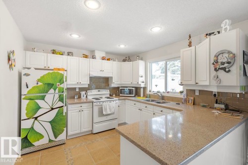 Kitchen with white cabinetry, recessed lighting, and a window above the sink - 44 9630 176 Street, Edmonton, AB 
