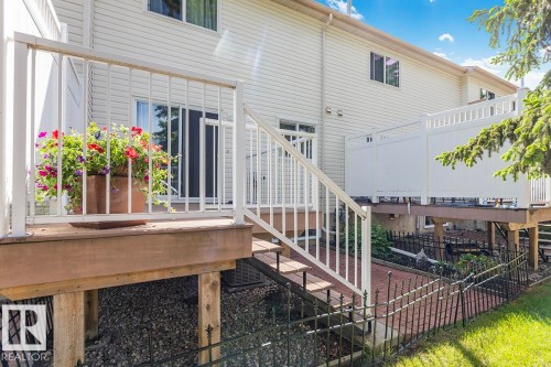 Multi-level deck with white railing, featuring exterior siding, sliding glass door, and staircase access - 44 9630 176 Street, Edmonton, AB 
