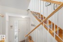 Entryway featuring a white paneled door with sidelight, overhead lighting, and a staircase with wood treads, patterned risers, and a wood handrail - 44 9630 176 Street, Edmonton, AB 