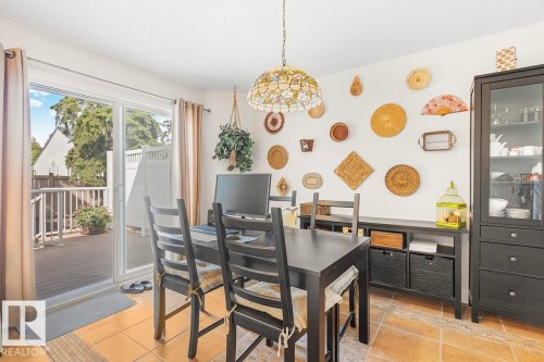 Dining area featuring terracotta-hued tile flooring and a stained-glass chandelier - 44 9630 176 Street, Edmonton, AB 