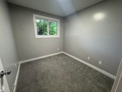 Bedroom featuring gray carpeting and a white-trimmed window - 6441 180 Street, Edmonton, AB 