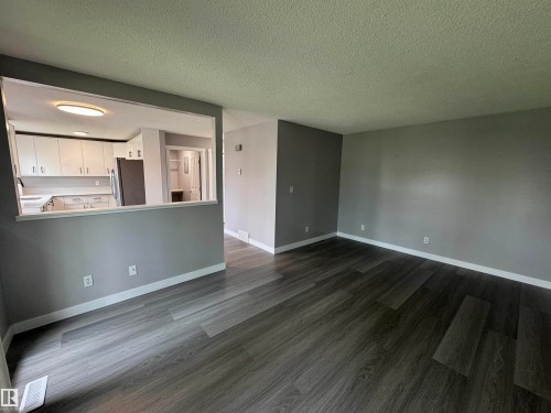 Open concept living space featuring modern wood-finish flooring and neutral gray wall tones - 6441 180 Street, Edmonton, AB 