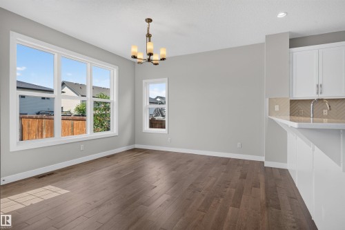 Expansive interior space featuring wood-finish flooring, white trim, and light gray wall paint - 9432 229 Street, Edmonton, AB 