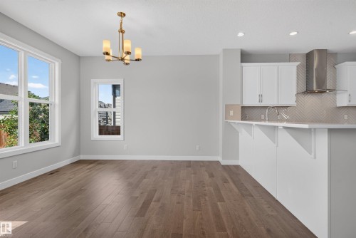 Open-concept living area featuring wood-finish flooring, a modern chandelier, and recessed lighting - 9432 229 Street, Edmonton, AB 