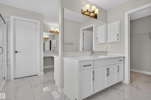 Bathroom vanity featuring white cabinetry, a single basin, and a light-colored countertop - 9432 229 Street, Edmonton, AB 