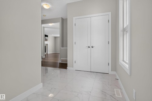 Foyer featuring large format tile flooring, a tall side window, and double panel doors - 9432 229 Street, Edmonton, AB 