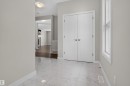 Foyer featuring large format tile flooring, a tall side window, and double panel doors - 9432 229 Street, Edmonton, AB 