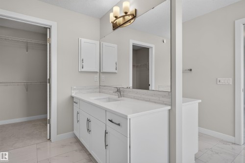 Bathroom vanity with dual undermount sinks, white cabinetry, and a light-colored countertop - 9432 229 Street, Edmonton, AB 