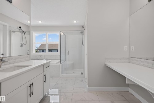 Bathroom featuring a double vanity with white cabinetry, white countertops, and black hardware - 9432 229 Street, Edmonton, AB 