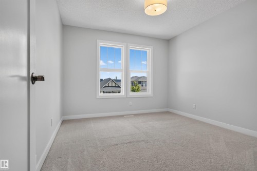 Bright room featuring neutral wall paint, light carpeting, white trim, a double window, and a flush mount light fixture - 9432 229 Street, Edmonton, AB 