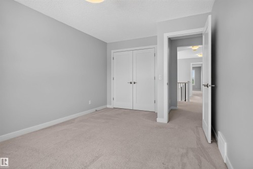 Carpeted room with light gray wall paint, featuring a double-door closet with contemporary hardware - 9432 229 Street, Edmonton, AB 