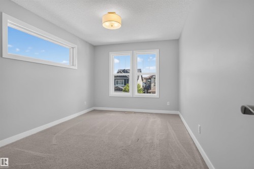 Carpeted room featuring light gray walls, white baseboards, and a semi-flush mount ceiling fixture - 9432 229 Street, Edmonton, AB 