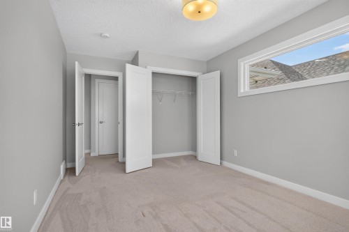 Carpeted room with light gray walls, a horizontal window, and a built-in closet with double bifold doors - 9432 229 Street, Edmonton, AB 