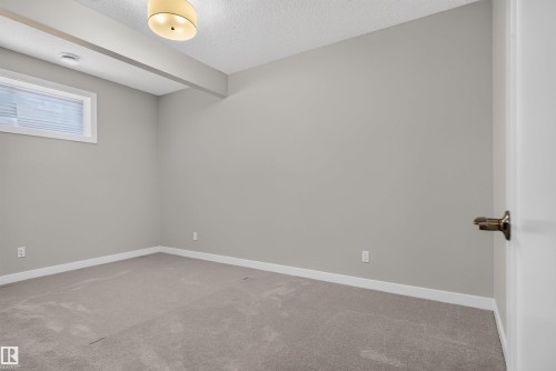 Neutral-toned room featuring a single window with blinds, light gray walls, and plush carpeting - 9432 229 Street, Edmonton, AB 