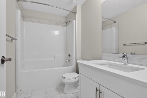 Bathroom featuring a white vanity with an integrated sink, chrome faucet, and subway tile backsplash - 9432 229 Street, Edmonton, AB 