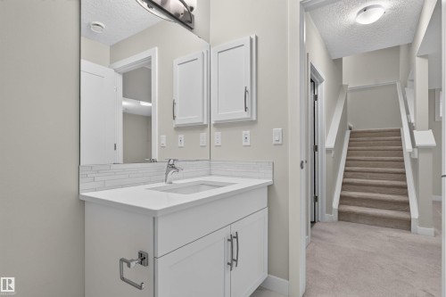 Bathroom vanity featuring white shaker-style cabinetry, a white countertop, and a subway tile backsplash - 9432 229 Street, Edmonton, AB 