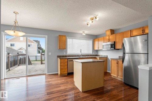 Kitchen featuring wood-finish flooring, a central island, light wood cabinetry, and stainless steel appliances - 7118 19A, Edmonton, AB - Indoor Photo Showing Kitchen With Double Sink
