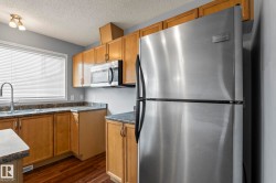 Kitchen featuring wood-finish cabinetry, speckled countertops, stainless steel appliances, and wood-finish flooring - 