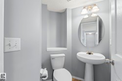 Pedestal sink with chrome faucet, oval mirror, and three-light vanity fixture - 
