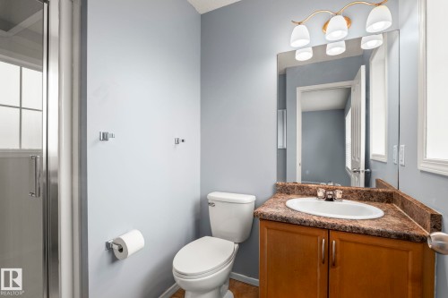Bathroom featuring a white toilet, wood-finish vanity with a built-in sink, and a light-toned countertop - 7118 19A, Edmonton, AB - Indoor Photo Showing Bathroom
