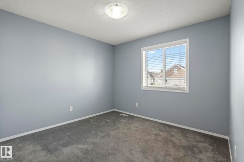 Bright room featuring a window with horizontal blinds, neutral-toned walls, and grey carpeting - 7118 19A, Edmonton, AB - Indoor Photo Showing Other Room