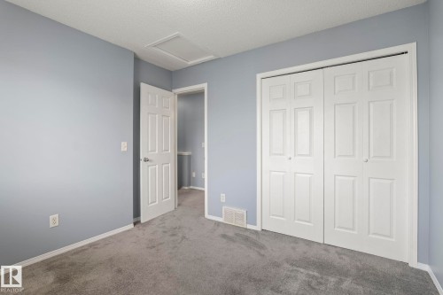 Room featuring light blue walls, gray carpet, white baseboards, and a white six-panel door with a silver handle - 7118 19A, Edmonton, AB - Indoor