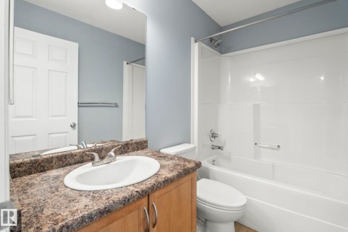 Bathroom featuring a wood-finish vanity with a laminate countertop and integrated sink - 7118 19A, Edmonton, AB - Indoor Photo Showing Bathroom