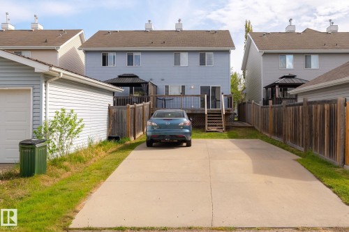 Rear exterior featuring a spacious concrete driveway, private wooden fencing, and a multi-level deck with a black gazebo - 7118 19A, Edmonton, AB - Outdoor