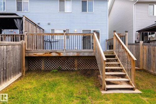 Wood-finish deck with stairs and lattice skirting, featuring a privacy fence and a grassy yard - 7118 19A, Edmonton, AB - Outdoor With Deck Patio Veranda With Exterior