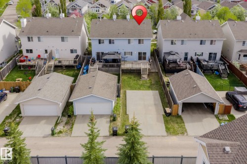 Rear exterior featuring a spacious wooden deck with stairs to the yard, fenced perimeter, and a detached two-car garage with a concrete driveway - 7118 19A, Edmonton, AB - Outdoor