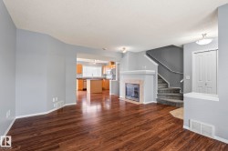 Open concept living area featuring dark wood-finish flooring, a gas fireplace with a light-toned tile surround, and a white mantel - 