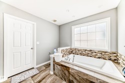Built-in soaking tub featuring a decorative mosaic tile surround and a large privacy window - 