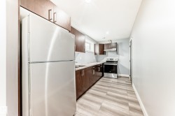 Kitchen featuring stainless steel appliances, dark wood cabinetry, light-toned countertops, wood-finish flooring, and a recessed ceiling light - 
