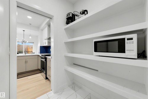 Integrated kitchen pantry featuring white built-in shelving and white tile flooring - 3173 Checknita Way, Edmonton, AB 