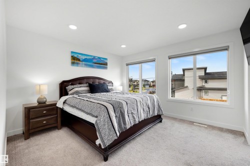 Bedroom featuring two large windows, recessed ceiling lighting, light gray carpeting, and white baseboards - 3173 Checknita Way, Edmonton, AB 