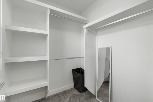 Walk-in closet featuring built-in shelving, multiple hanging rods, and grey carpeting - 3173 Checknita Way, Edmonton, AB 