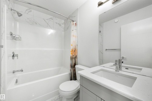 Bathroom featuring a vanity with an integrated rectangular sink, chrome faucet, and expansive mirror - 3173 Checknita Way, Edmonton, AB 