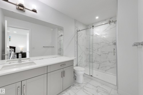 Contemporary bathroom featuring a spacious vanity with a built-in sink, light gray cabinetry, and a full-width mirror - 3173 Checknita Way, Edmonton, AB 