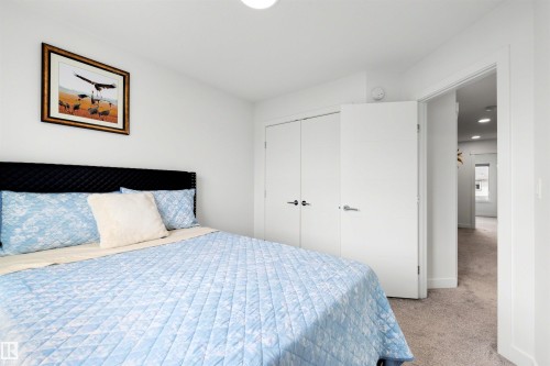 Carpeted interior room featuring a padded headboard, dual-door closet, and white walls - 3173 Checknita Way, Edmonton, AB 