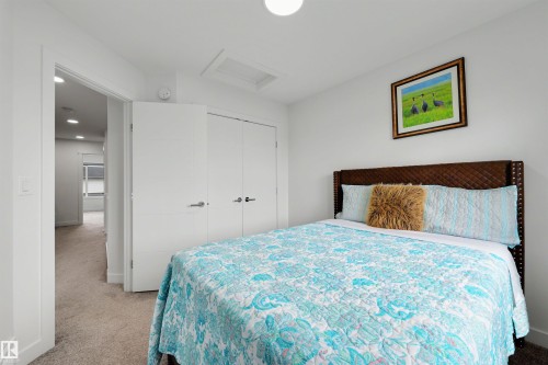 Carpeted room with a ceiling-mounted light fixture, white walls, and a pair of white closet doors with brushed nickel hardware - 3173 Checknita Way, Edmonton, AB 