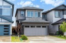 Contemporary home exterior featuring gray siding with dark trim accents, a matching garage door, and a stone facade detail - 3173 Checknita Way, Edmonton, AB 