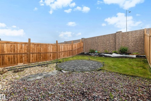 Spacious backyard featuring a circular paver patio, mixed gravel and grass landscaping, and a wood privacy fence - 3173 Checknita Way, Edmonton, AB 