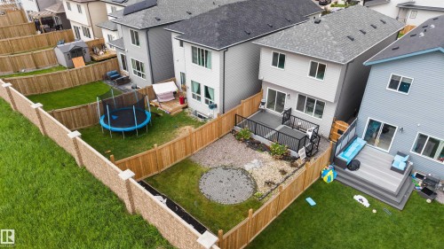 Expansive fenced backyard featuring a multi-level composite deck with dark railings, a paved circular patio area, and a rock garden - 3173 Checknita Way, Edmonton, AB 