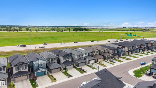 Modern suburban streetscape featuring contemporary homes with attached garages, paved driveways, and manicured front landscaping - 3173 Checknita Way, Edmonton, AB 
