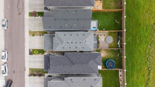 Aerial perspective showcasing multiple properties with shingle roofs, individual concrete driveways, and fenced backyards - 3173 Checknita Way, Edmonton, AB 